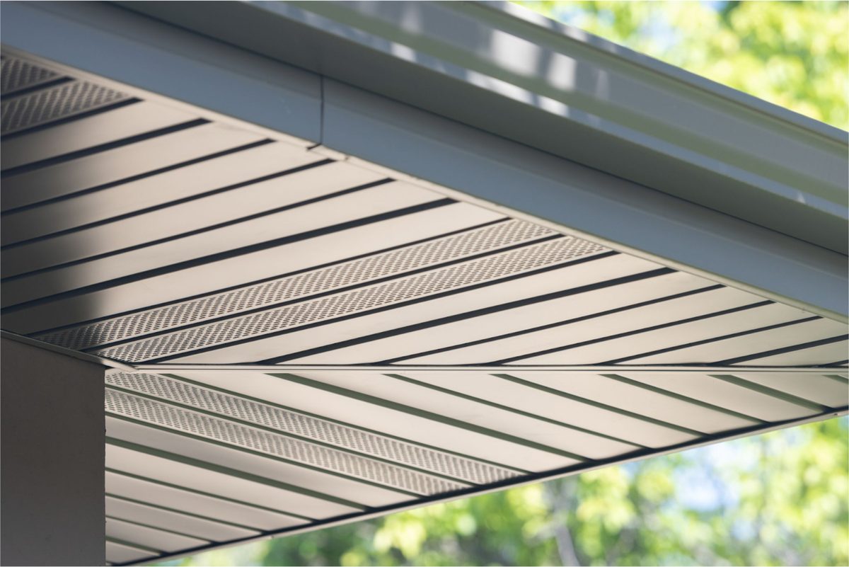 Technician installing vented aluminum soffit on a Tampa Bay home eave
